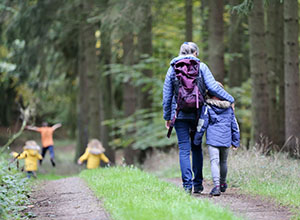 Family walking on a trail in the woods.