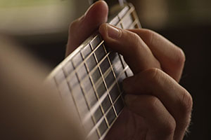 Closeup of fingers on the fretboard of a guitar.